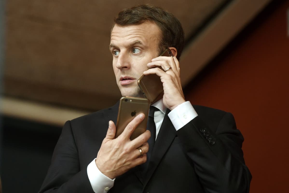 Lähikuva presidentti Emmanuel Macronista kädessään yksi kännykkä, korvalla toinen.