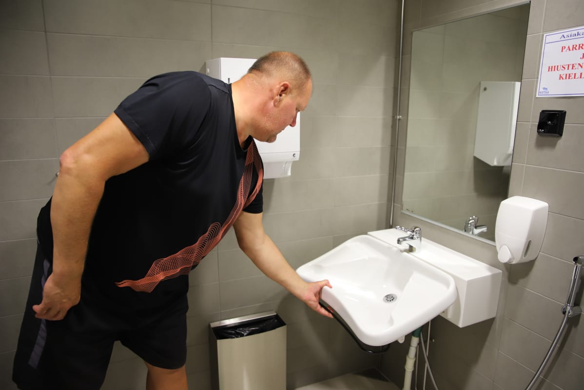 Laitosmies Mika Riikonen näyttää, miten kääntyvä lavuaari toimii.