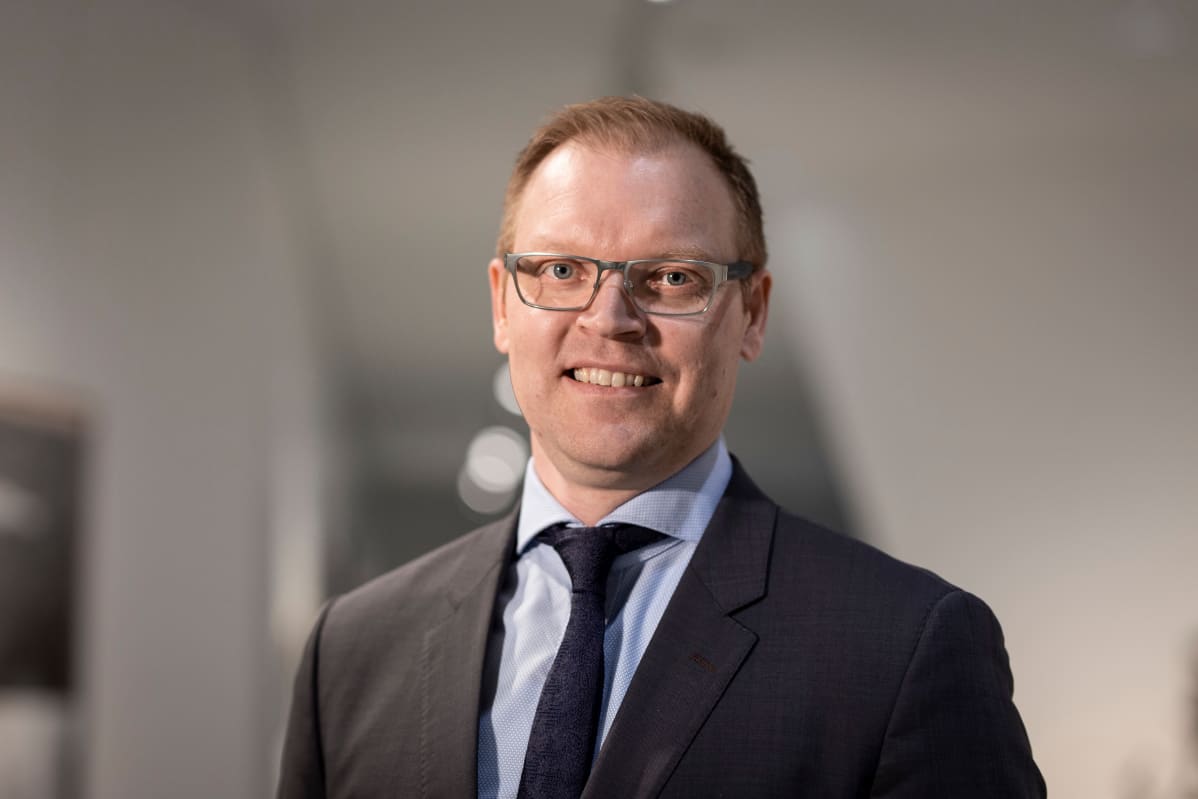 Tuomas Virtala työskentelee johtajana OP Yrityspankissa. Kuvassa hän seisoo OP:n pääkonttorin valoisassa aulassa Helsingin Vallilassa ja katsoo kameraan.
