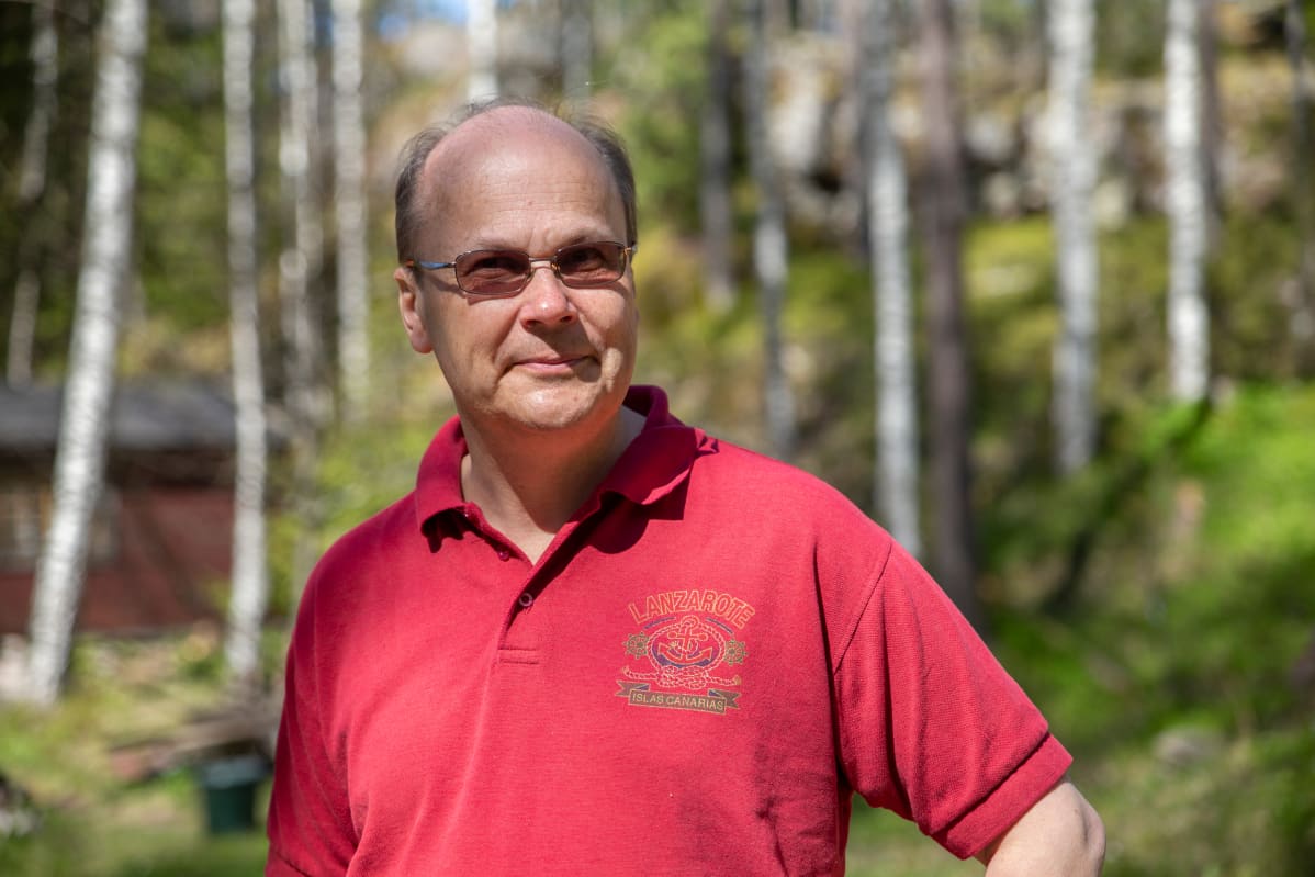 Ekonomisti Roger Wessman seisoo ulkosalla tummat lasit silmillään yllään lyhythihainen punainen pikeepaita.