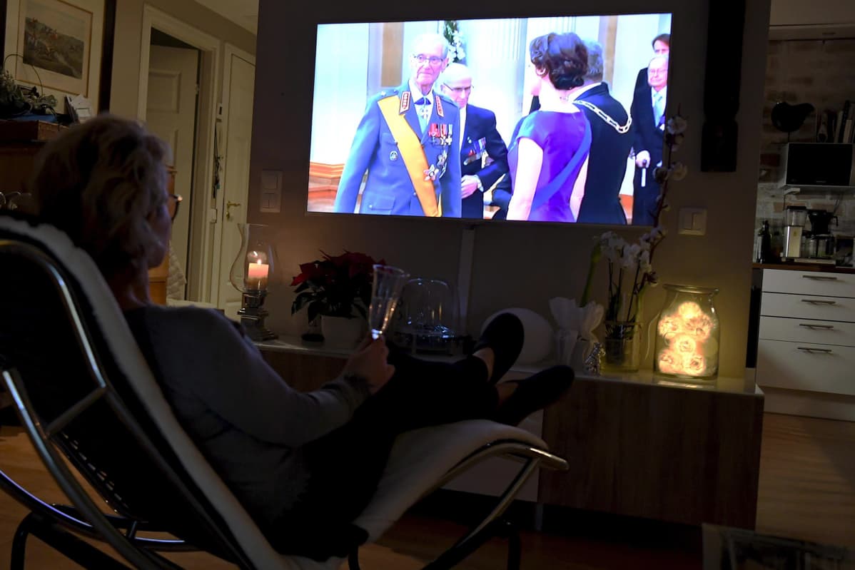 Nainen viettää itsenäisyyspäivää seuraamalla TV:stä Ylen lähetystä.