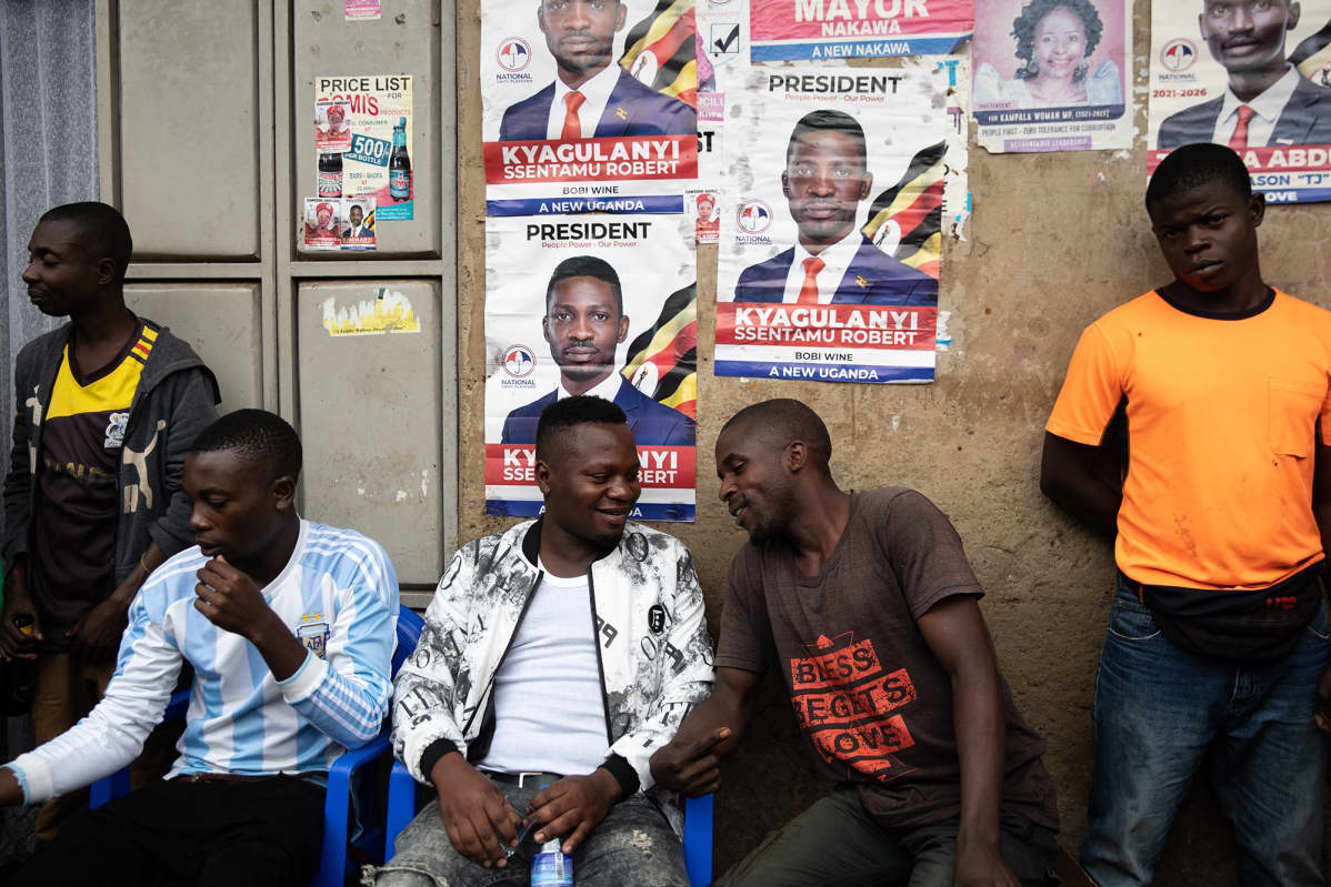 Alan Mugisa istuu ystäviensä kanssa Kamwokyan slummialueella, missä Bobi WIne kasvoi.