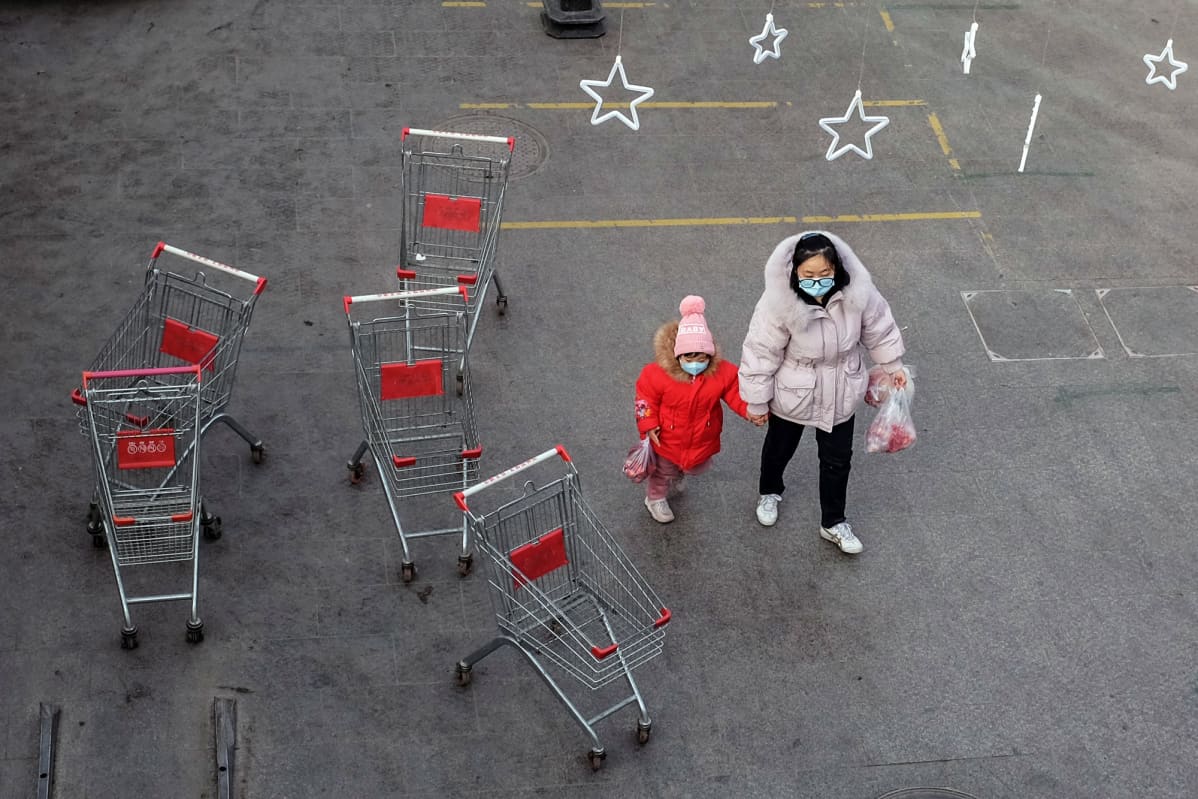 Nainen taluttaa lasta marketin ulkopuolella Pekingissä.