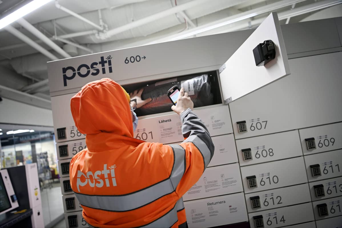 Postin työntekijä lajittelee paketteja pakettiautomaattiin Helsingissä 14. joulukuuta.