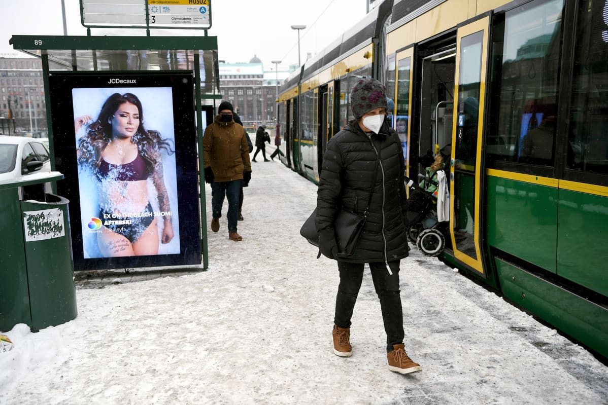 Matkustajia raitiovaunupysäkillä Helsingin keskustassa.