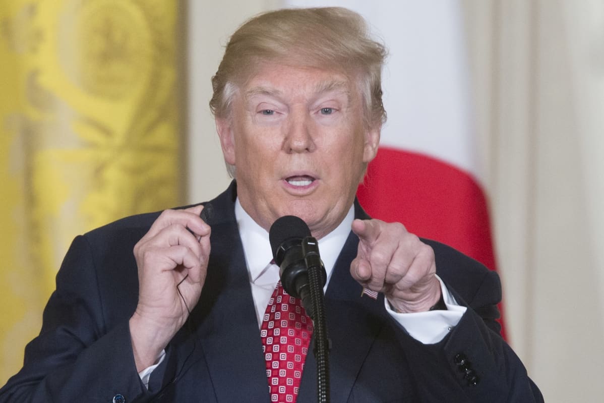 Donald Trump mikrofonin takana, osoittaa sormelle eteenpäin.