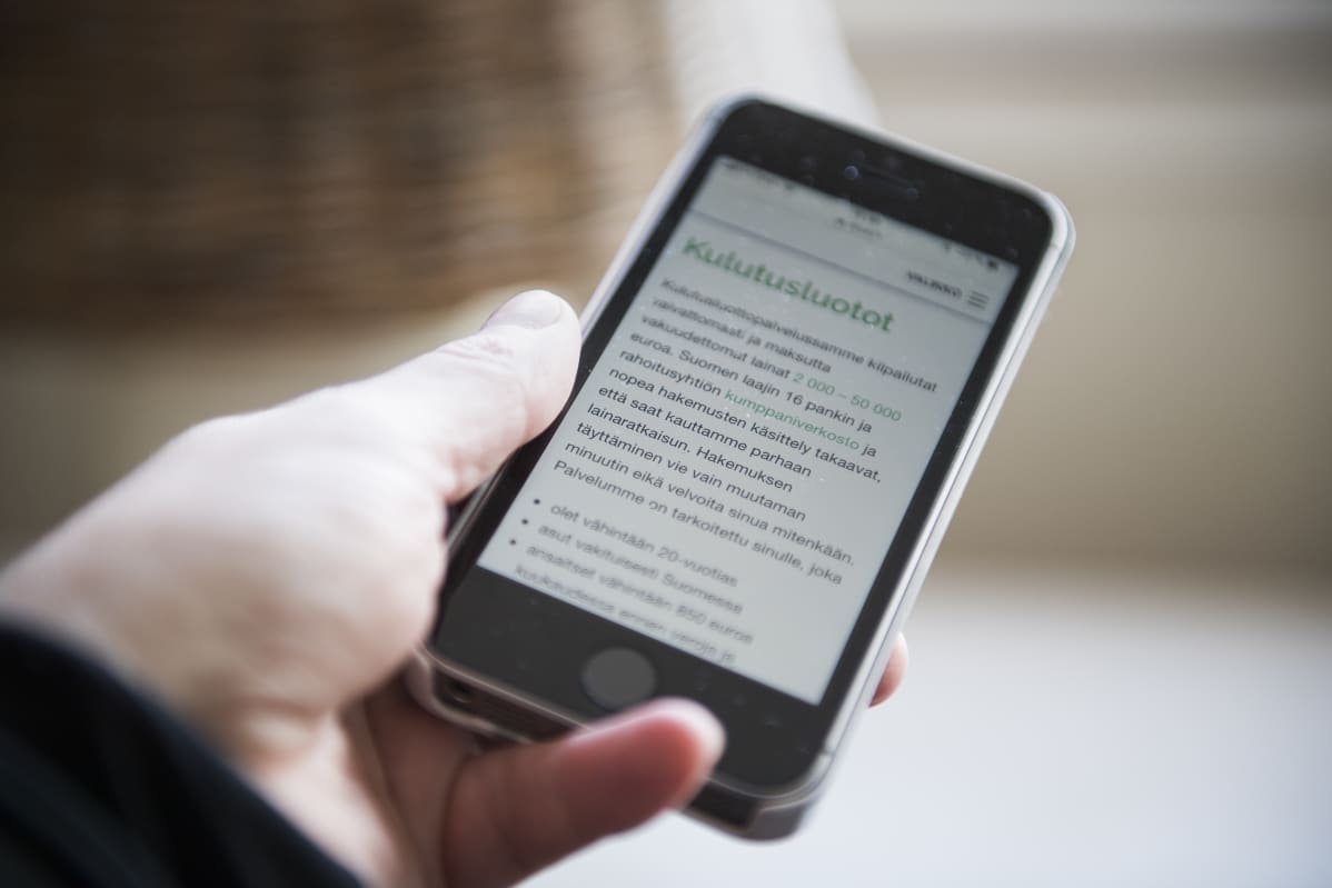 nainen katsoo puhelimesta kulutusluoton mahdollisuuksia