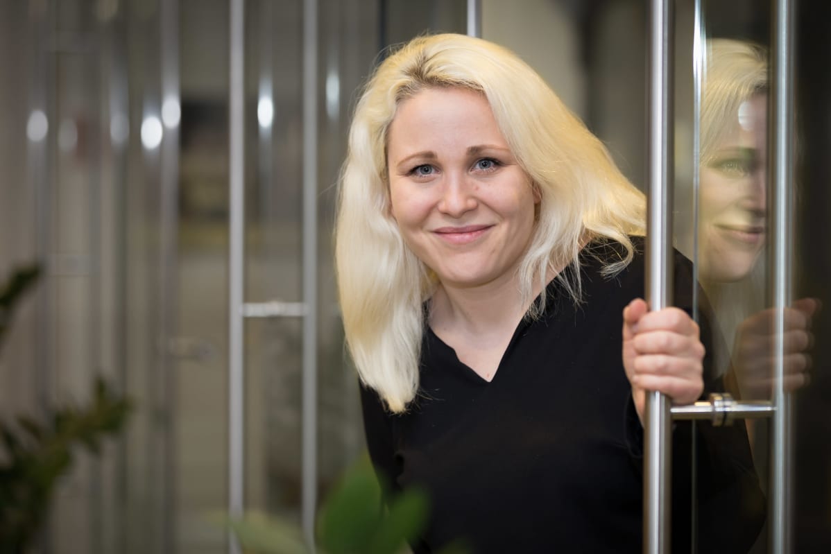 Taru Tukiainen kurkkaa oven välistä.