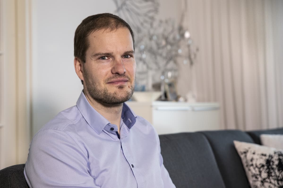 Mies istuu kotisohvalla