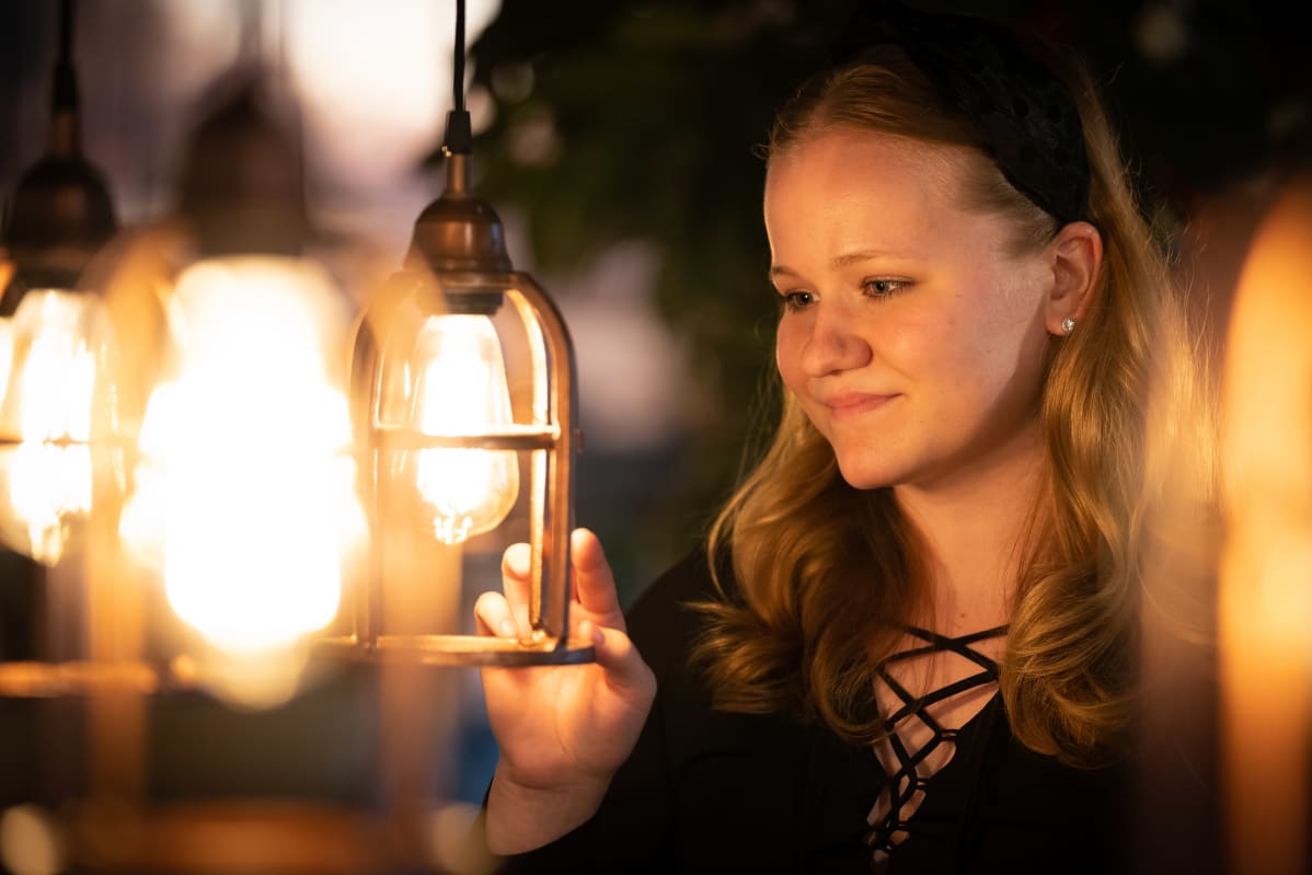 Amanda Laakkonen sisustuslamppujen keskellä.