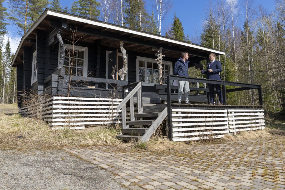 Esittelijä ja asiakas myytävän mökin terassilla.