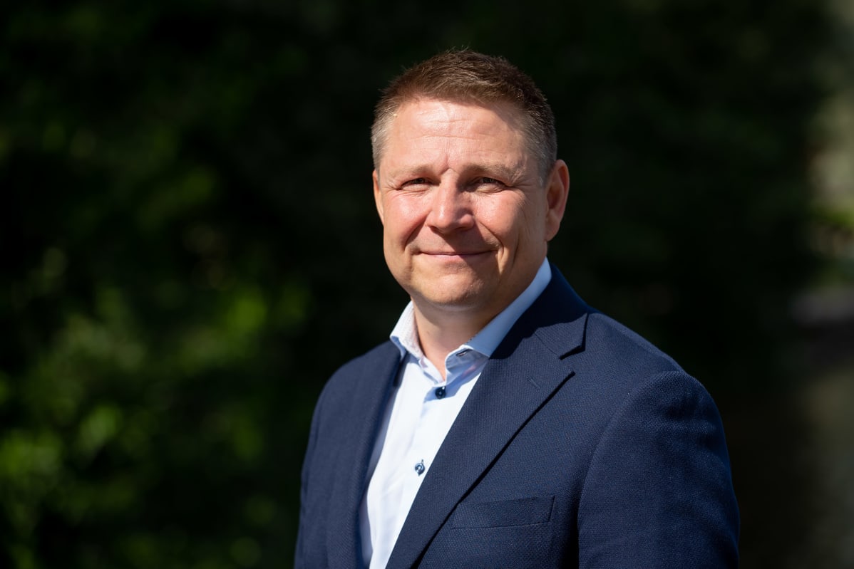 Juha Jokela seisoo puku päällä katsoo kameraan.