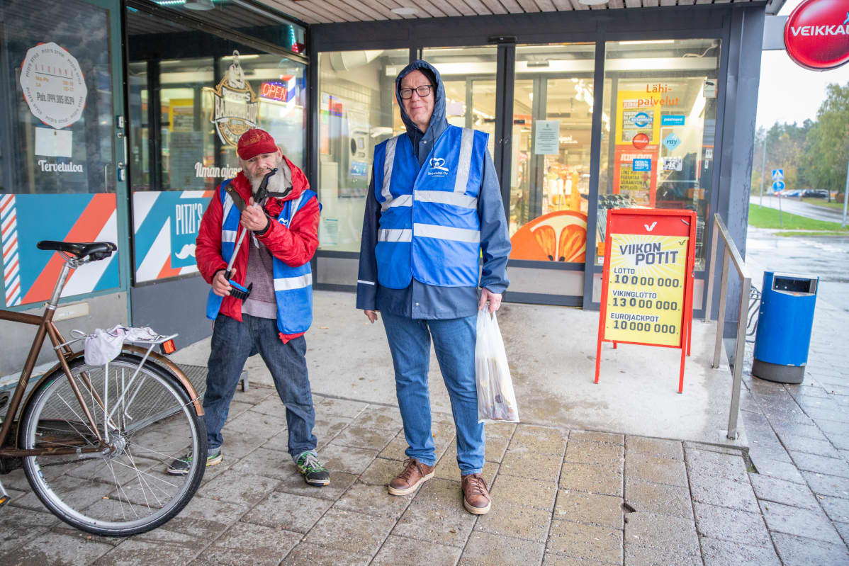 Niittykodin asukas Jarmo ja ympäristötyöntekijä Pekka Kiuru seisovat paikallisen kaupan edustalla.