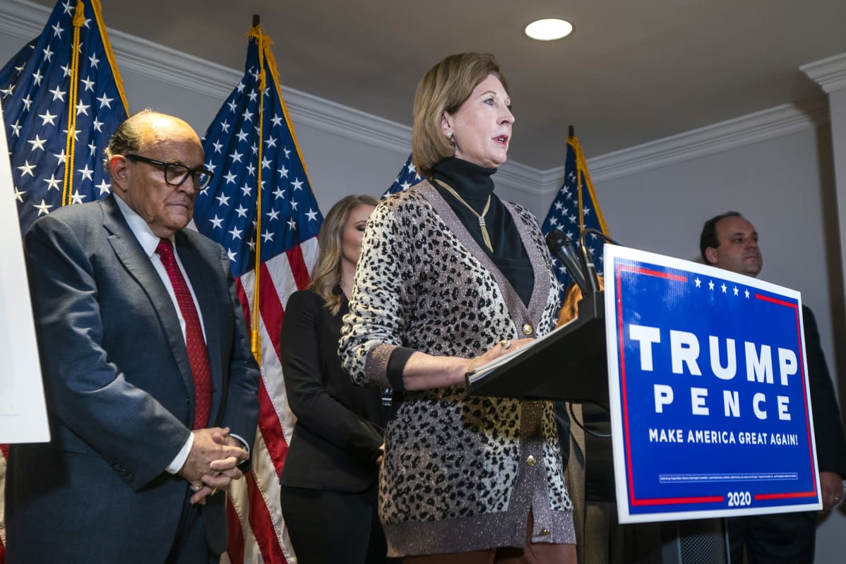 Trumpin asianajaja Sidney Powell puhuu lehdistötilaisuudessa. Vasemmalla taustalla kuvassa Rudy Giuliani.