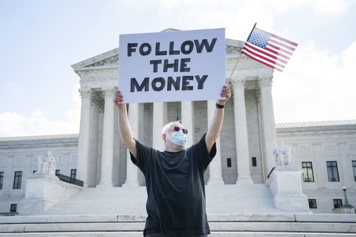 Follow the money -kylttiä kannatteleva mielenosoittaja Yhdysvaltain korkeimman oikeuden edessä heinäkuussa 2020. Trump yrittänyt saada korkeinta oikeutta estämään verotietojensa toimittamisen syyttäjälle..