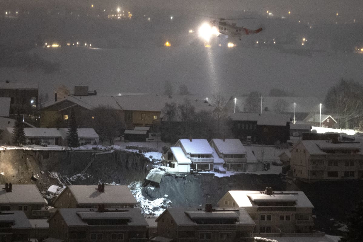 Helikopteri valaisee maanvyörypaikkaa.