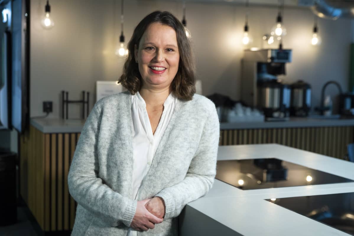 SOK:n kehityspäällikkö Mia Laakso nojaa pöydän kulmaan ja katsoo hymyillen kameraan.
