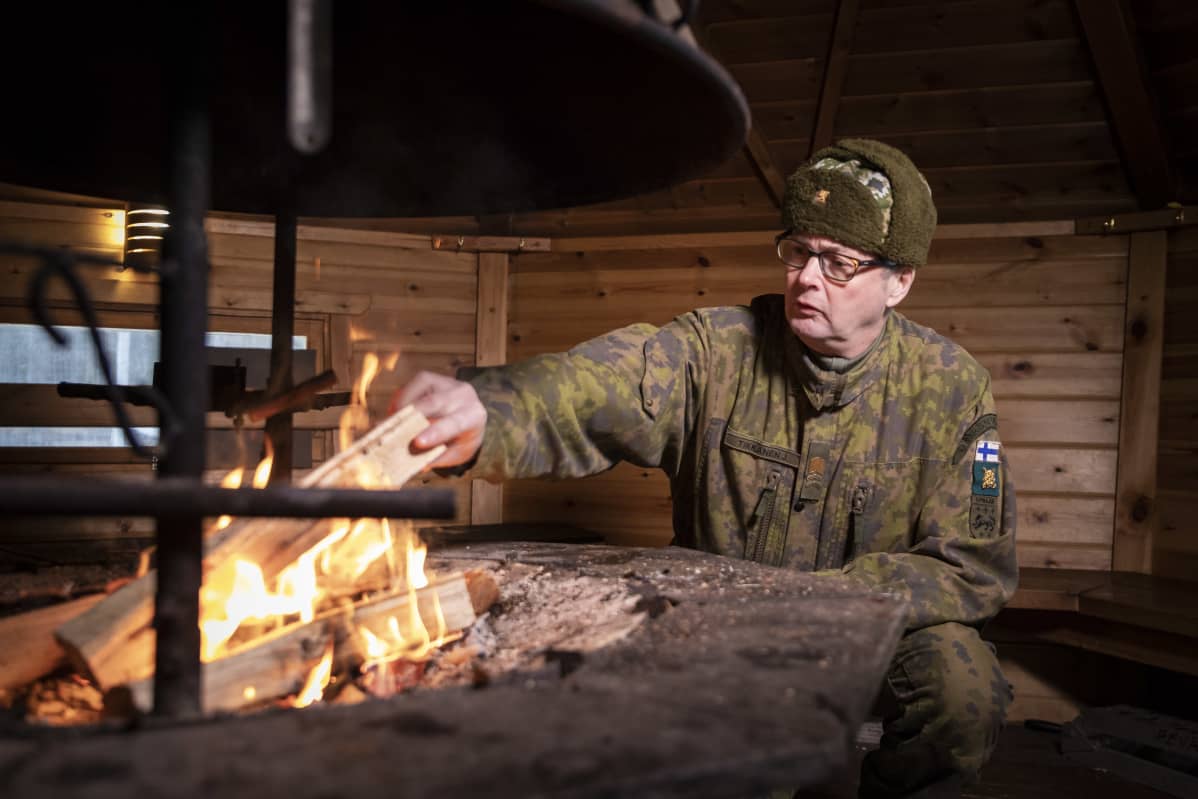 Jari Tikkanen lisää puita tuleen.