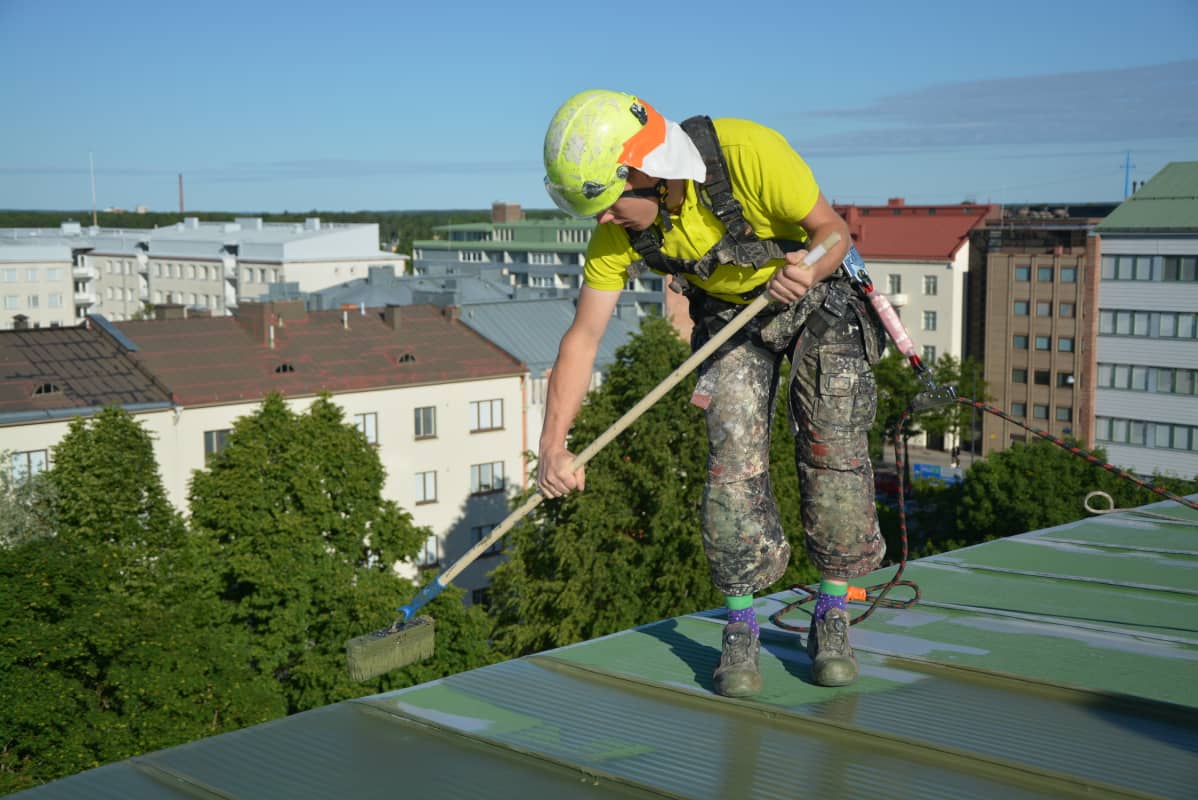 Antti Tervo maalaa kerrostalon kattoa Vaasassa.