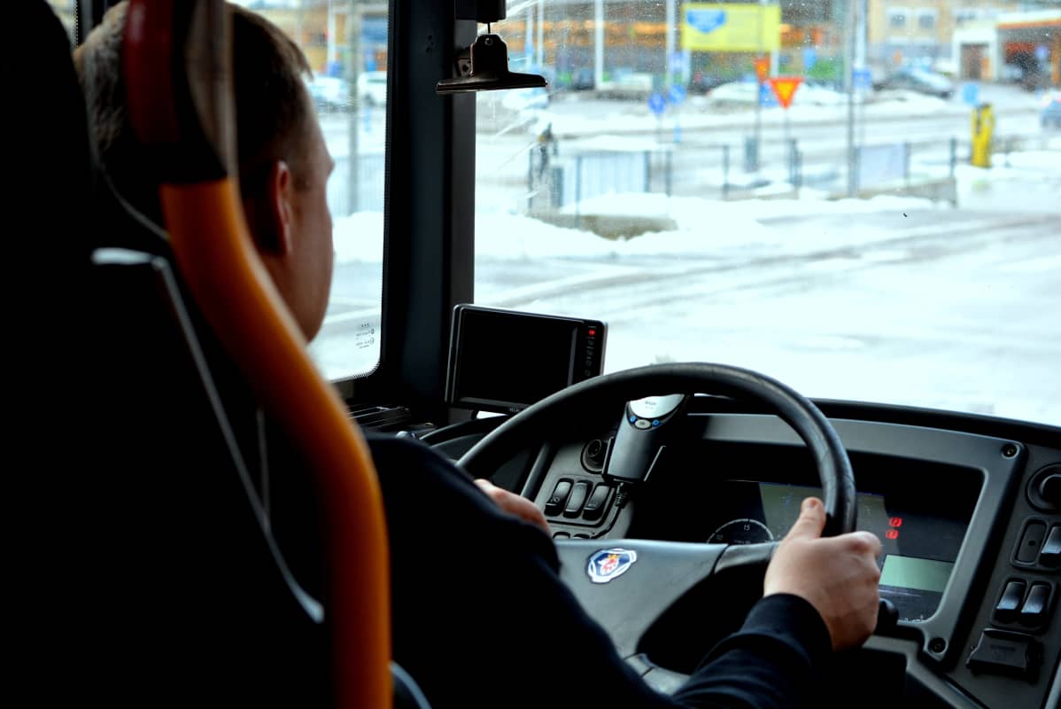 Busschaufför bakifrån vid ratt. Utsikt mot gata i Ekenäs.