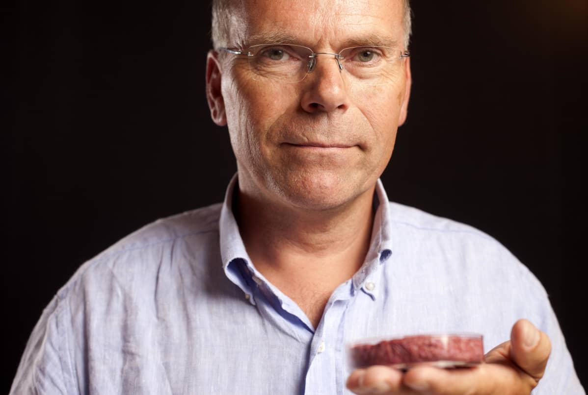 Professori pitää kädessään astiaa, jossa on laboratoriossa kasvatettua lihaa