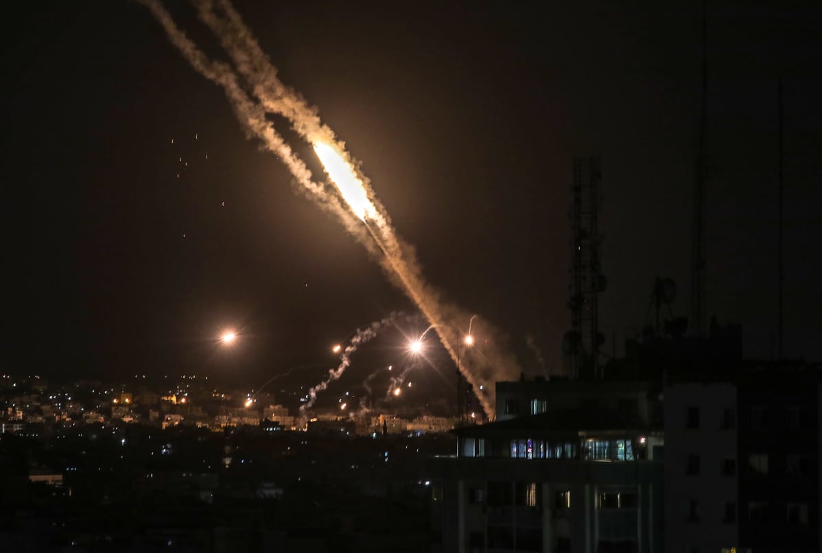 Palestiinalaisten Hamas ampuu raketin kohti Israelia ja raketti valaisee Gazan kaupungin yötaivaan.