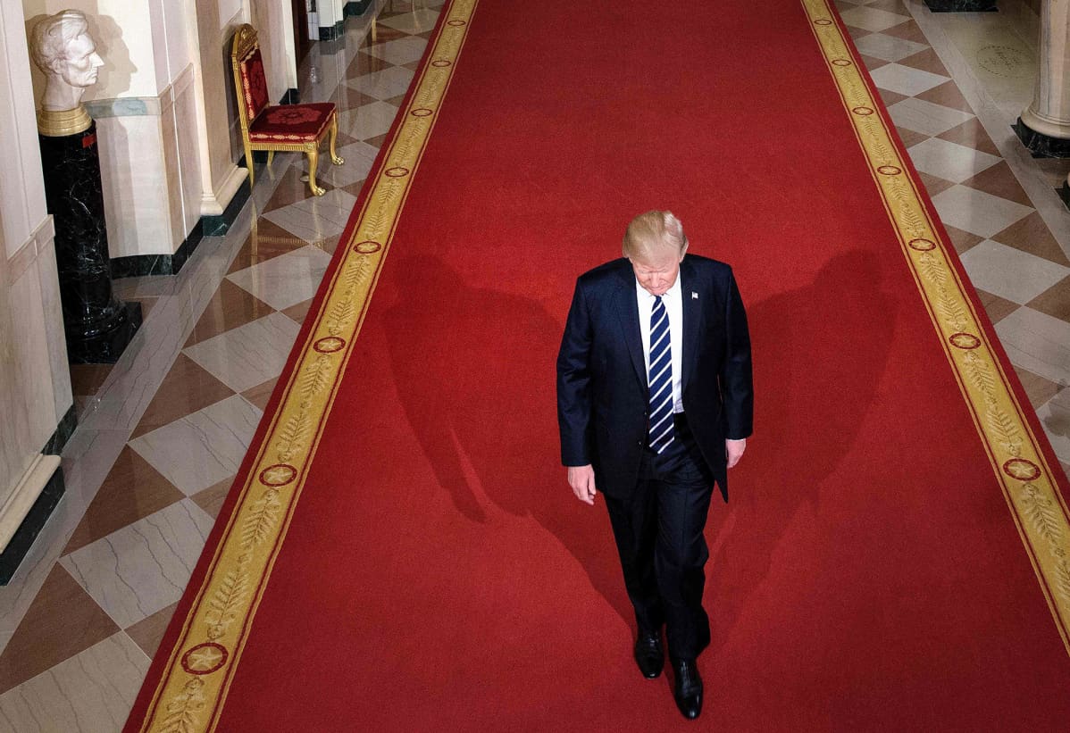 Donald Trump kävelee valkoisen talon käytävällä.