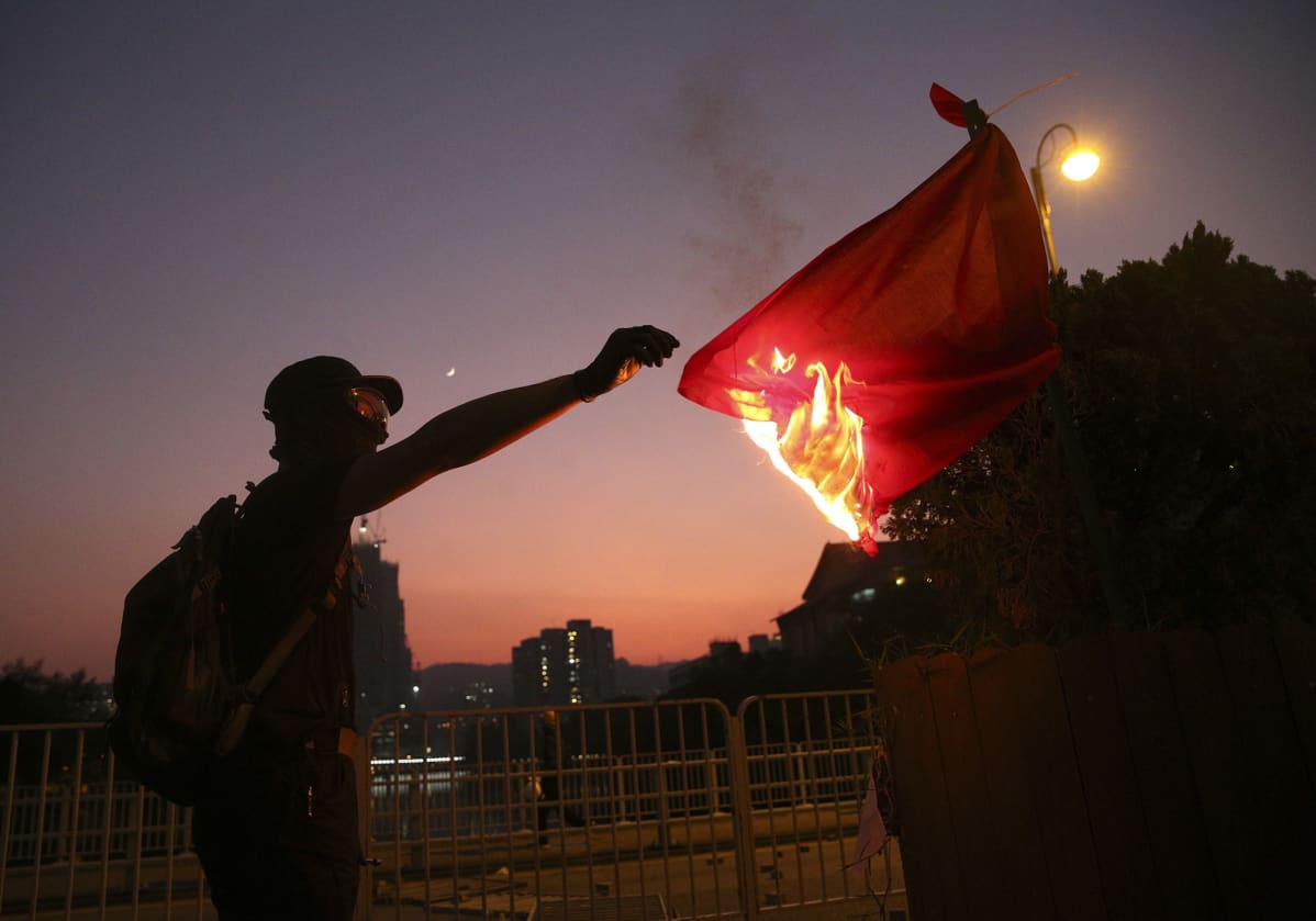 Mielenosoittaja sytyttää Kiinan lippua tuleen 1. lokakuuta Hongkongissa.