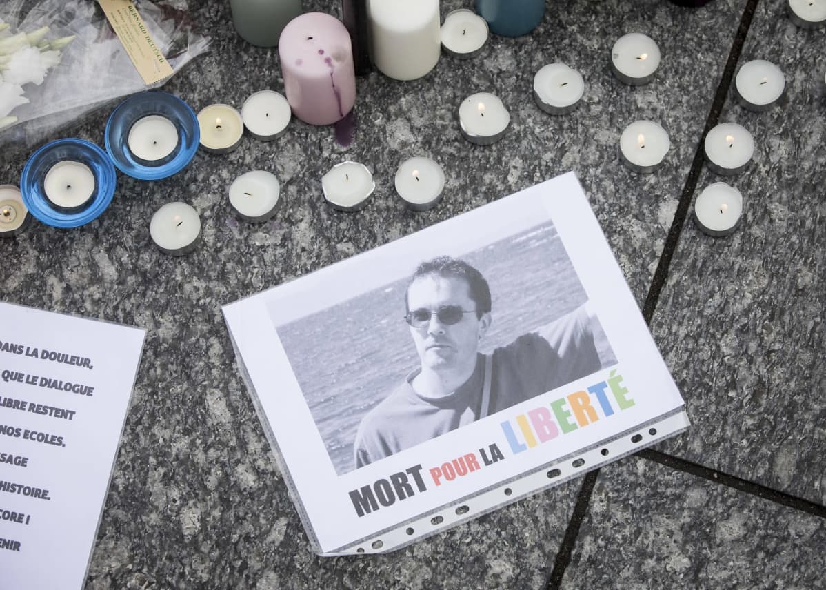 Kynttilöitä ja Samuel Patyn kuva, jonka alalaidassa lukee ranskaksi "Kuollut vapauden puolesta"