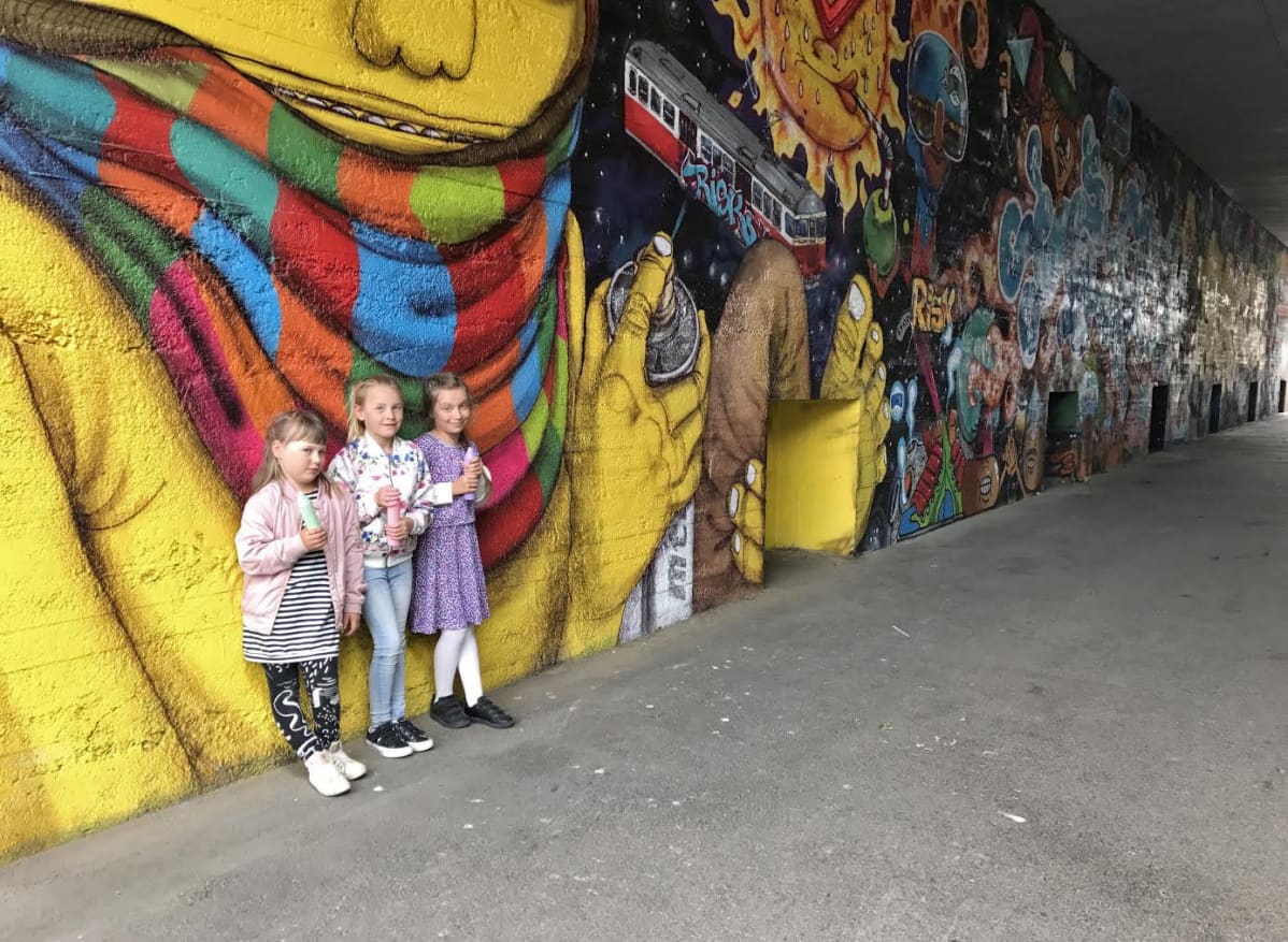 Kolme lasta graffitiseinän edessä.