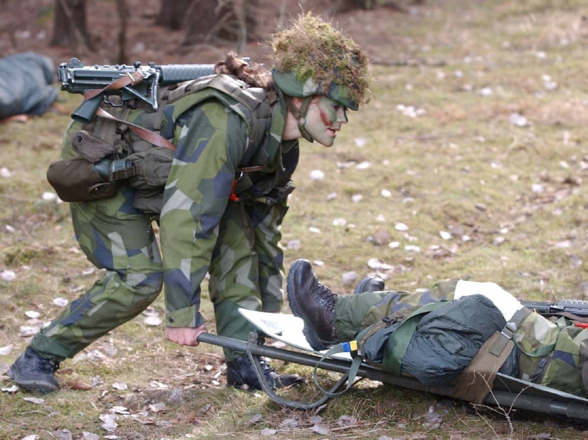 Maastopukeutunut Victoria kumartuu kantamaan paareja.