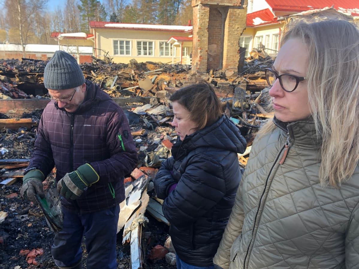 Pekka Ojanen, Tanja Sipilä ja Outi Pennanen tarkastelevat palaneen koulun raunioita.