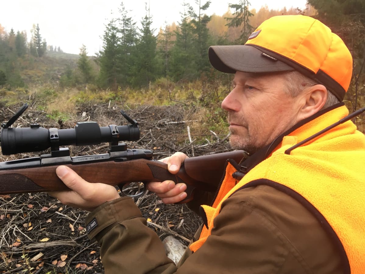 hirvenmetsästäjä passissa metsän laidalla aseen kanssa