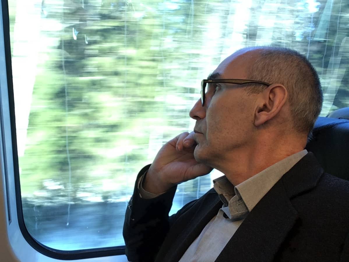 Juha T. Hakala istuu junassa ja tuijottaa ulos ikkunasta.