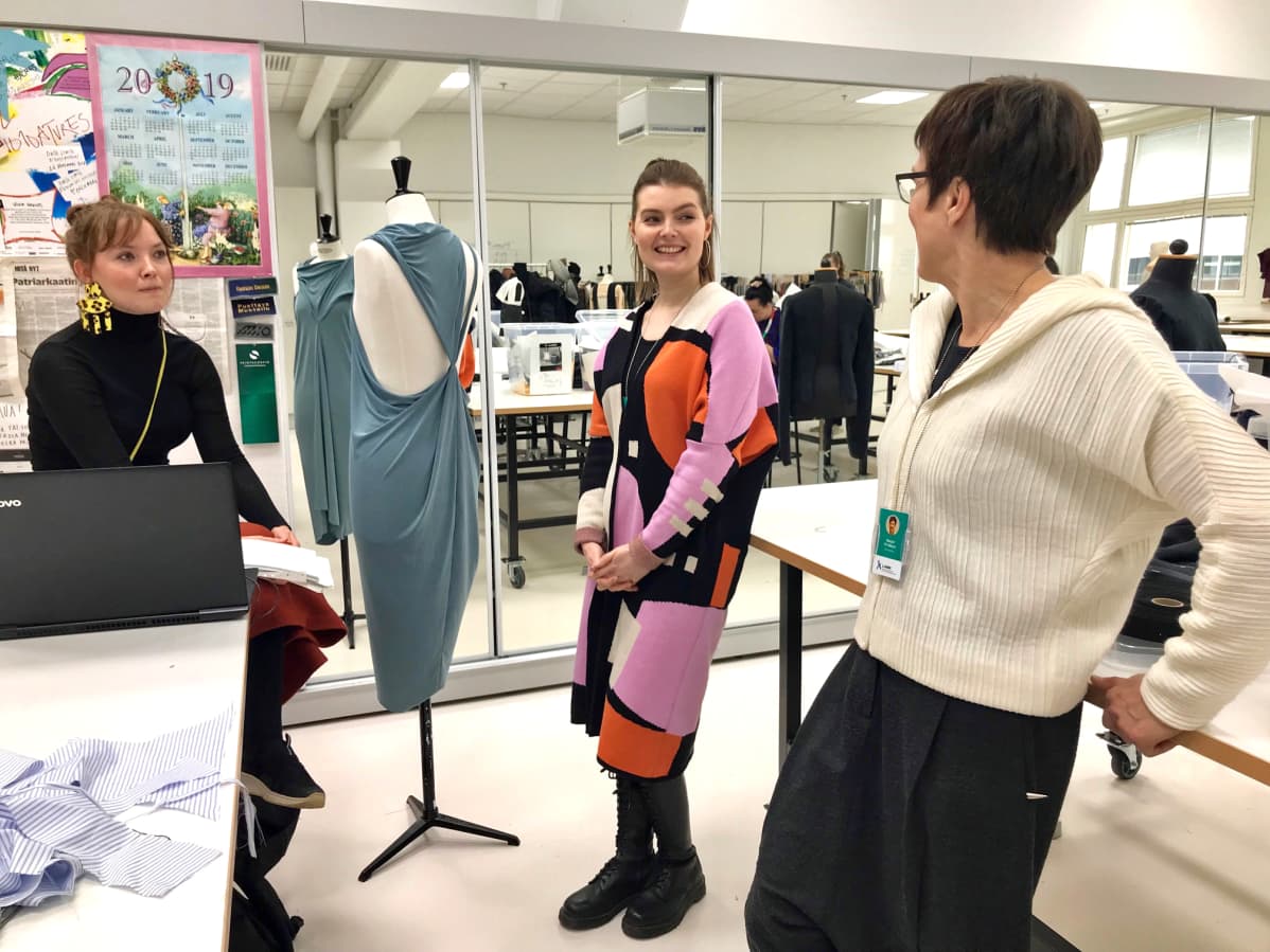 Veera Konga, Annariina Ruokamo ja Marjut Yli-Mäyry tarkastelevat Kongan suunnittelemaa mekkoa.