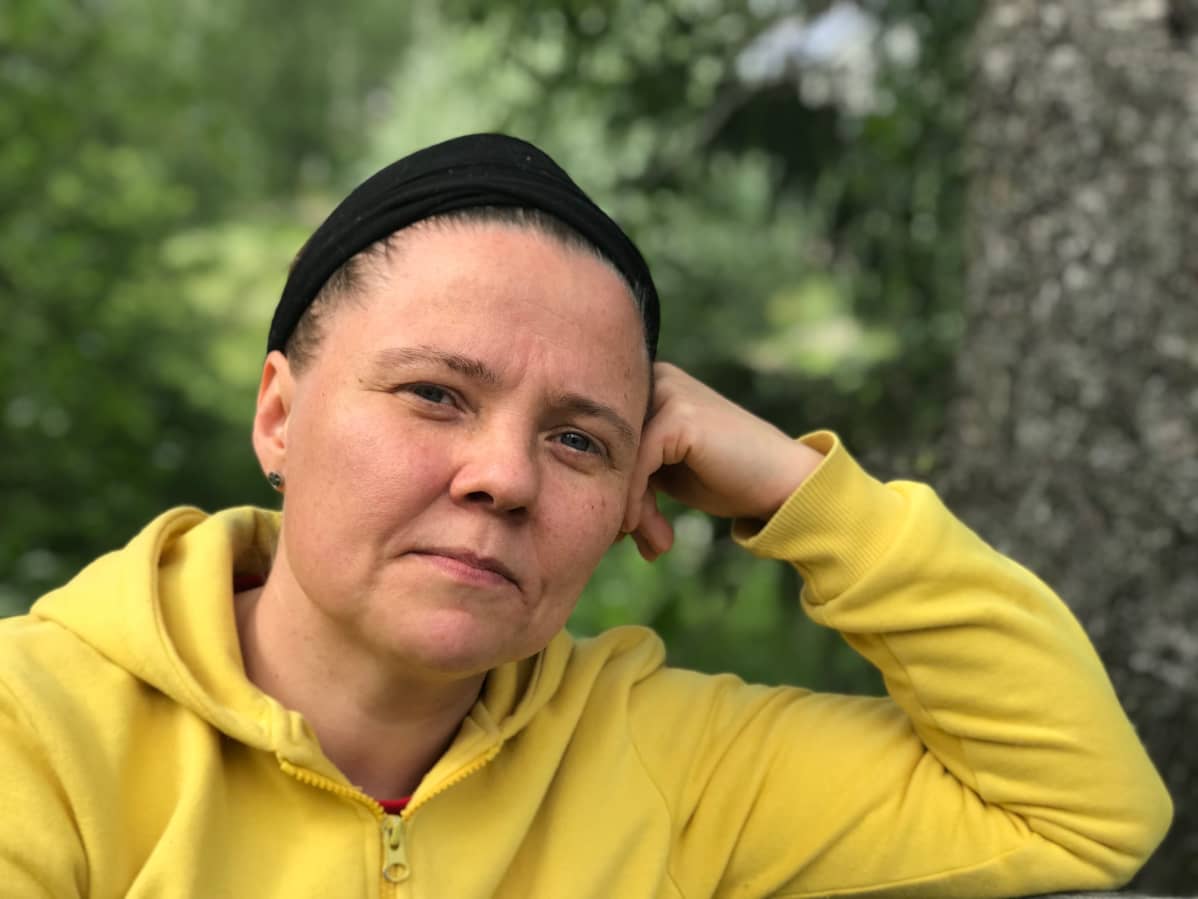 Annulii Koponen istuu penkillä puutarhassa ja katsoo kameraan