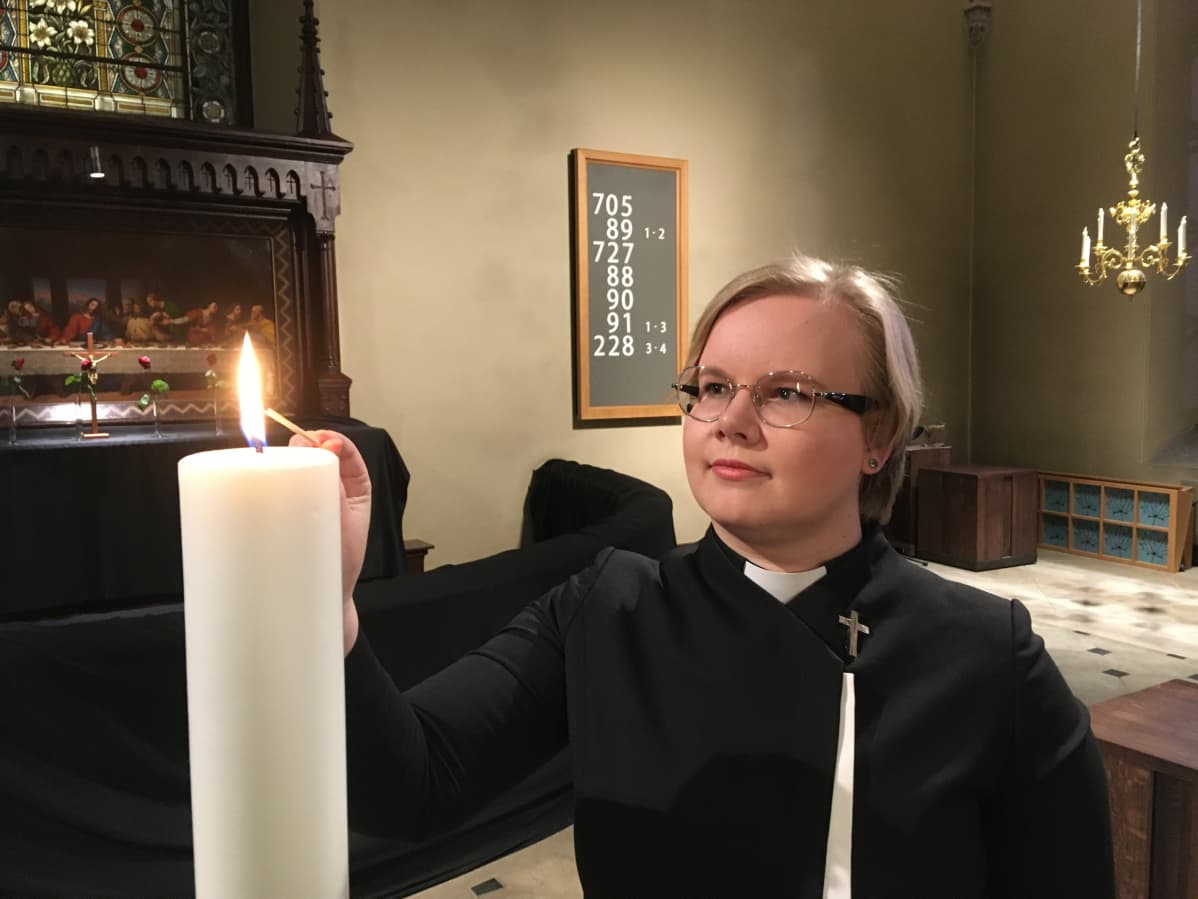 Pappi sytyttää kynttiläm pääsiäisyön messussa Pyhän Laurin kirkossa Vantaalla.