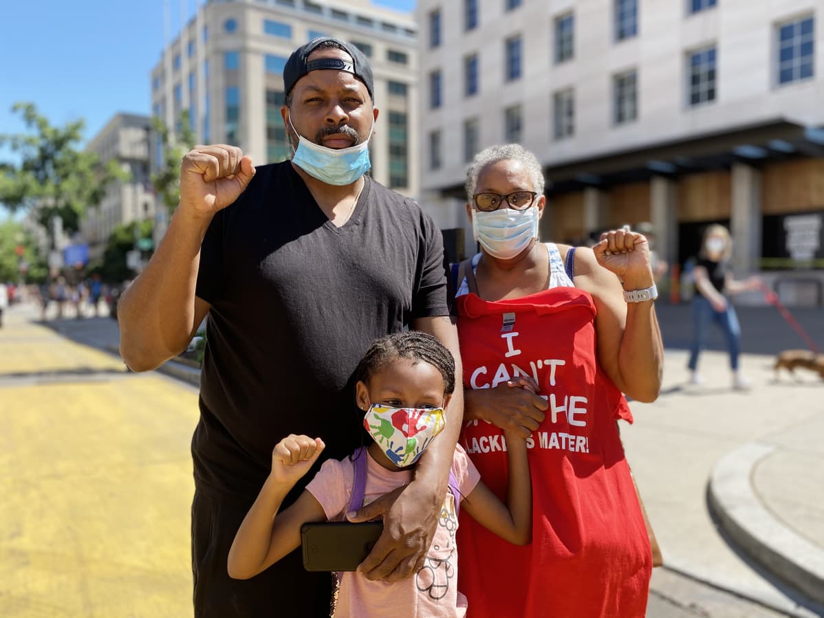 Corey Jordan, Carolyn Jackson ja 7-vuotias Bailey Jordan nostavat kätensä nyrkissä pystyyn Black Lives Matter -liikkeen symbolina.