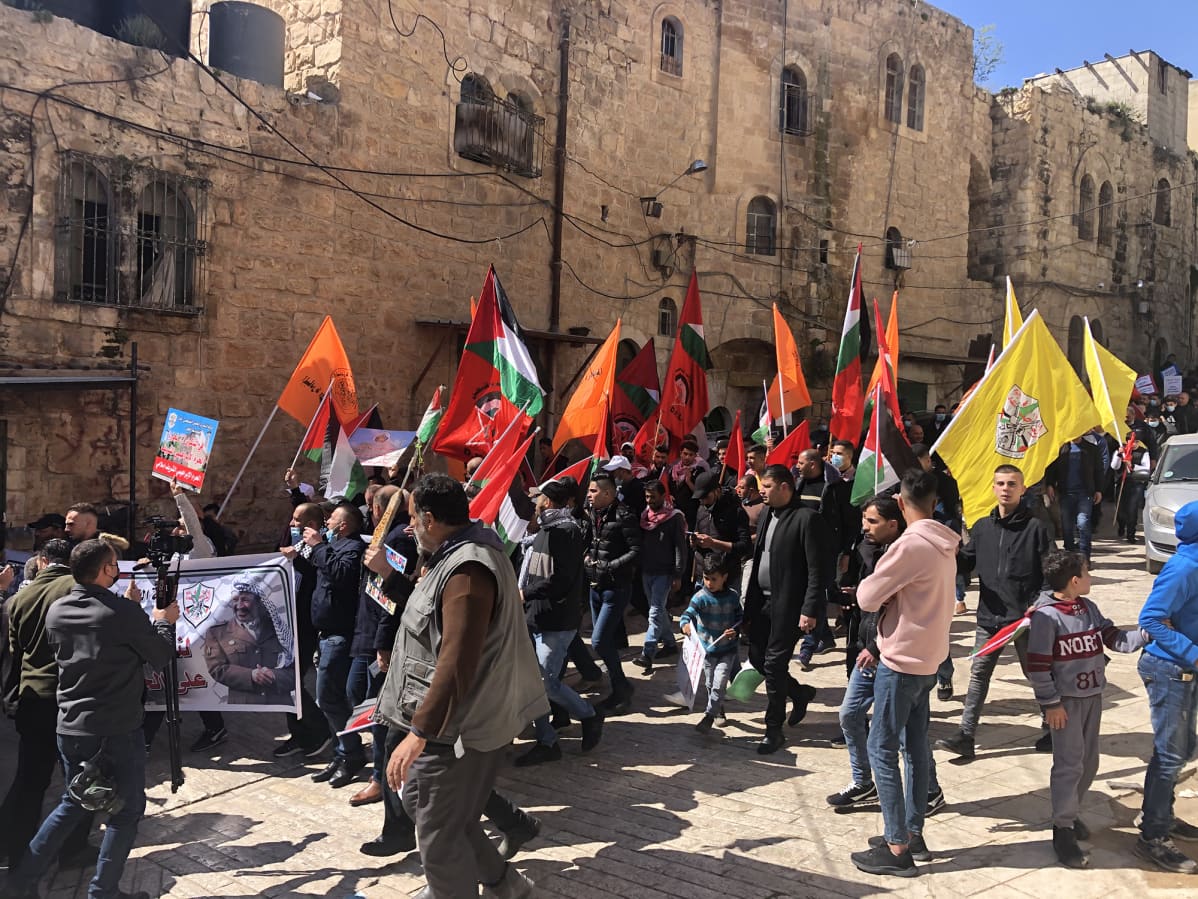 Hebronissa asuvat palestiinalaiset heiluttavat mielenosoituksessa lippujaan