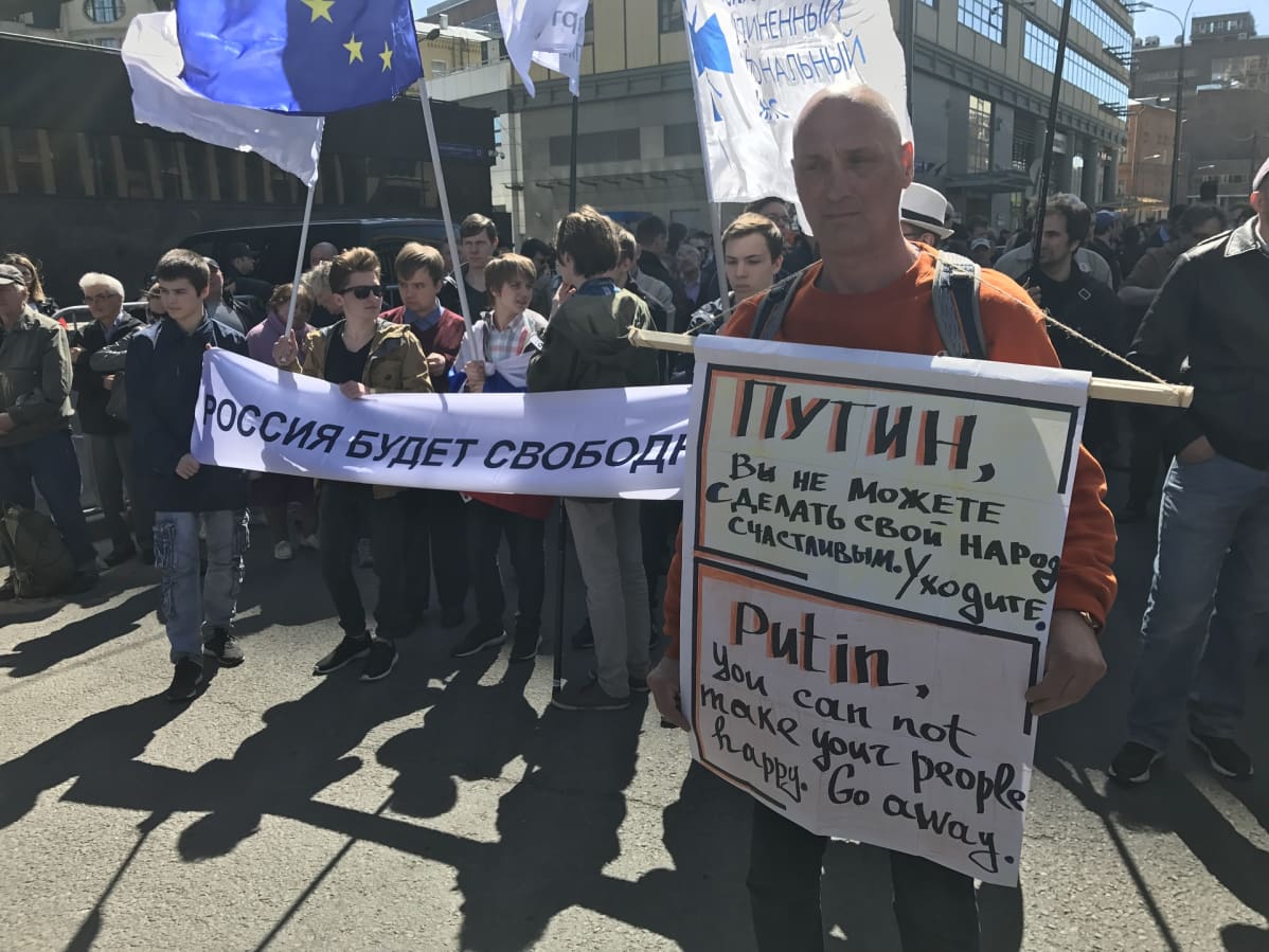 Mies, jolla Putinin eroa vaativa kyltti. Taustalla mielenosoittajia ja EU-lippu.