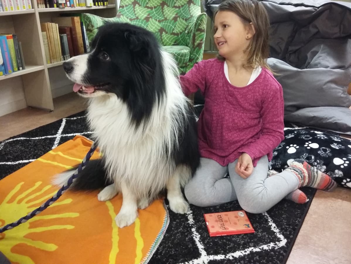 Flicka och hund sitter på golvet.
