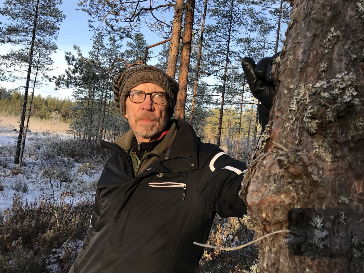 Luontokuvaaja Olli Korhonen nojaa puuhun.