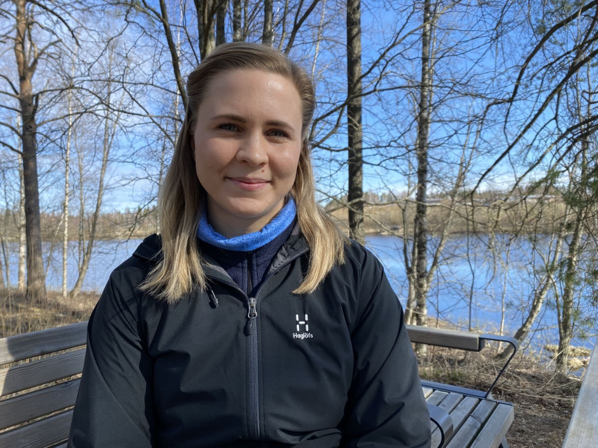 Laura Honkanen istuu auringonpaisteessa ulkona penkillä.