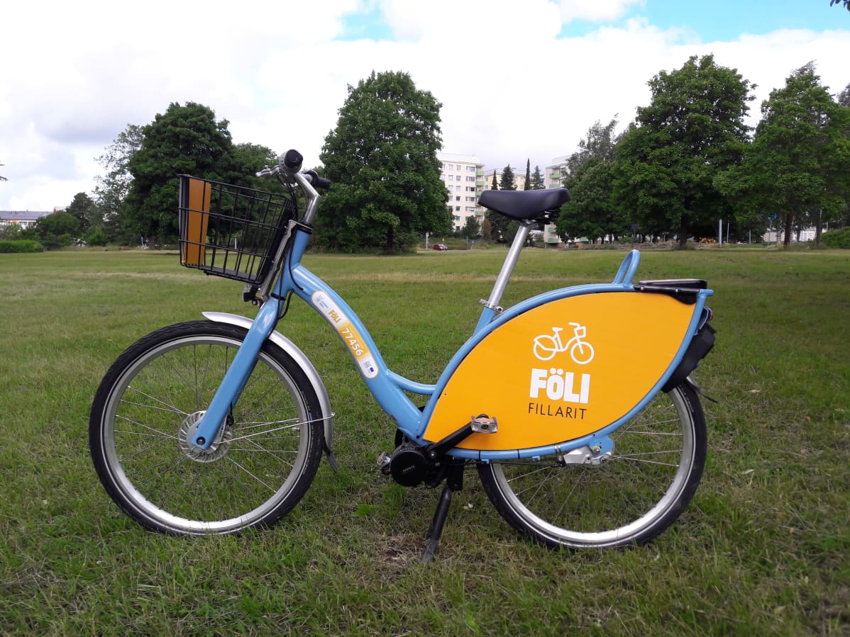 En blågul eFölläri-cykel står på en gräsmatta.