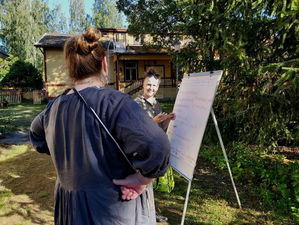 Talkoisiin saapuneita fläppi-taulun edessä.
