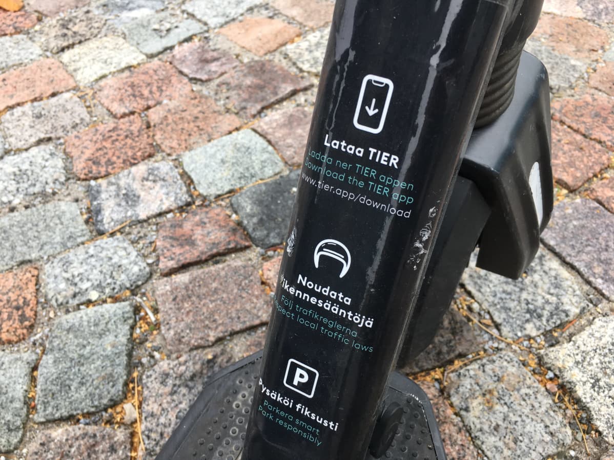 Tarra sähköpotkulaudan kyljessä jossa muistutus noudattaa liikennesääntöjä sekä pysäköidä fiksusti