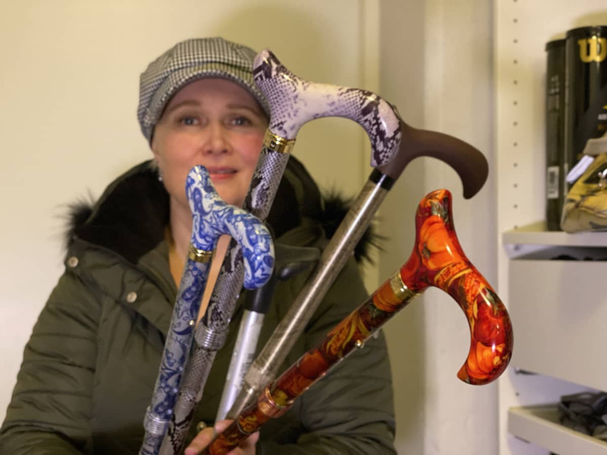 Anne Christiansen pitää kädessään sinivalkoista, mustavalkoista, ruskeaa ja punakuvioista keppiä.