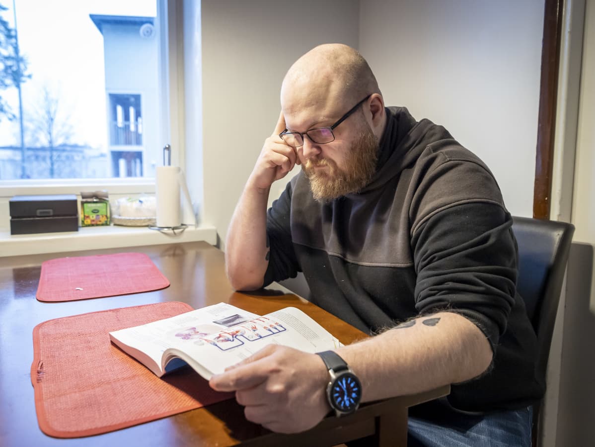 Janne Ostonen lukee oppikirjaa keittiön pöydän ääressä.