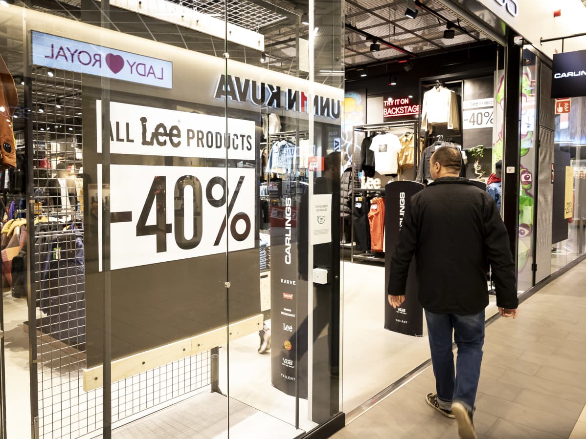 -40% -alennuskyltti vaatekaupan ikkunassa ja asiakas menossa kauppaan.
