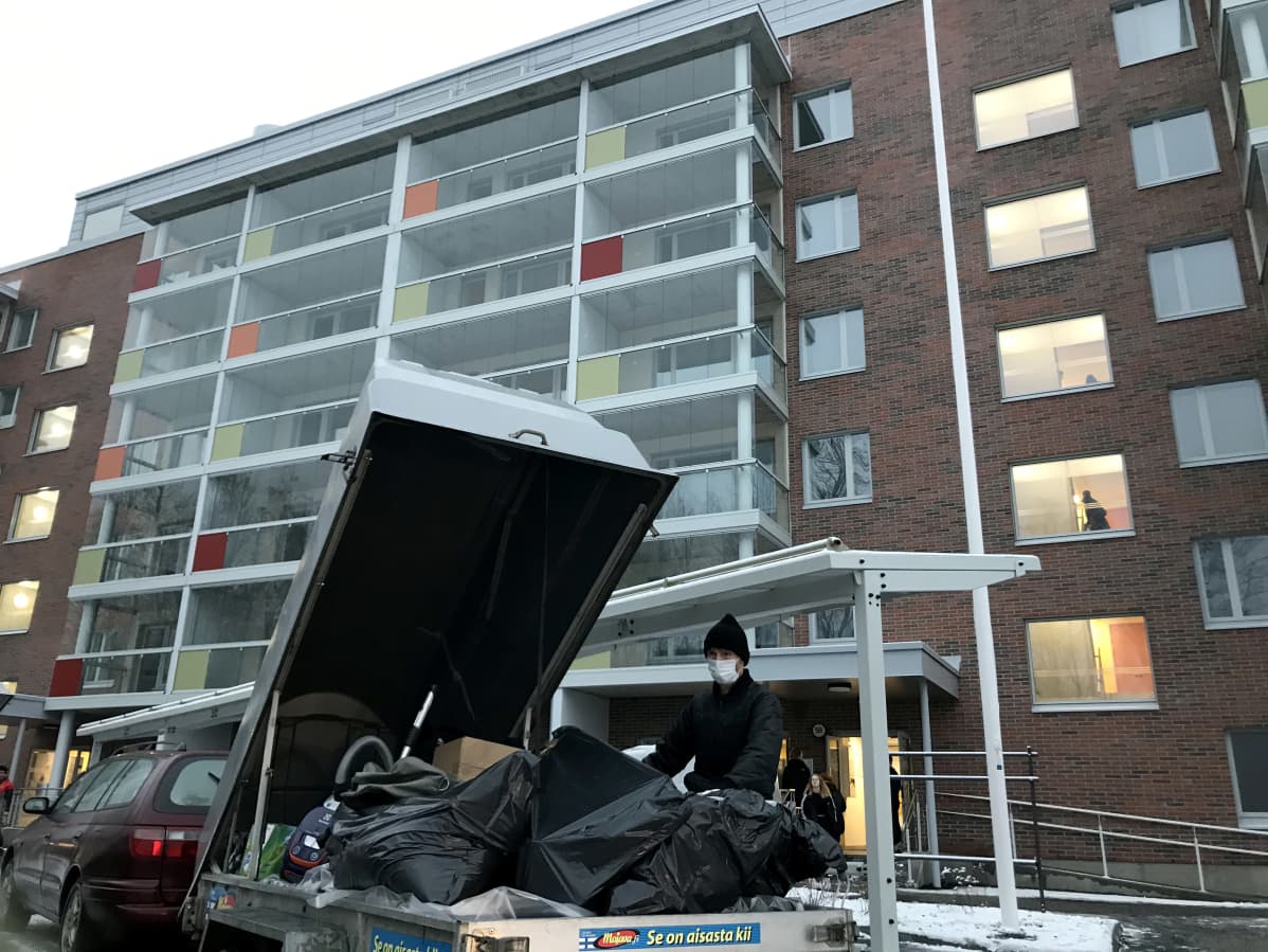 Muuttaminen menossa, mies peräkärryn äärellä kerrostalon edustalla